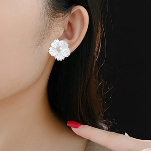 Gros plan de boucles d'oreilles fleur en nacre avec une petite perle centrale