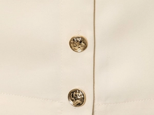 Detalle de chaleco tejido beige con elegantes botones dorados y costuras refinadas