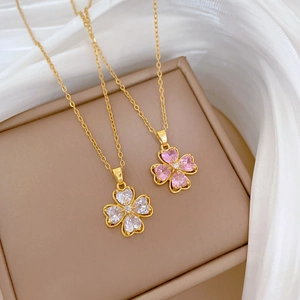 Detailed close-up of clover pendants with pink and white zircons on golden steel chains