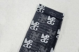 Close-up of black mesh bodysuit showing white abstract symbols and stitching detail