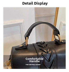 Close-up of black leather saddle bag featuring a woven handle and gold metal hardware
