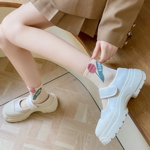 White platform Mary Jane shoes paired with beige floral ankle socks on wooden steps