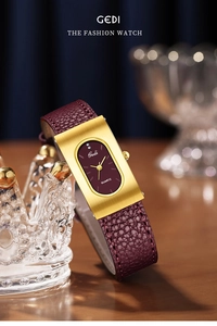 Macro detail of oval burgundy dial and gold rectangular casing with leather strap