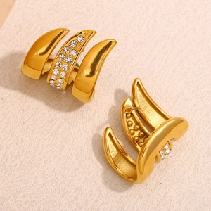 Macro shot of 18K gold plated claw earrings with cubic zirconia inlay on leather texture