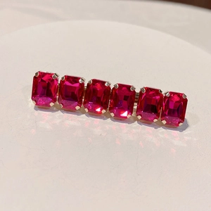 Detailed view of pink rectangular crystal hair clip on elegant gold metal base