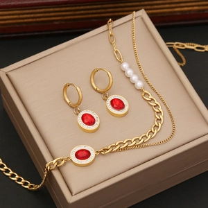 Golden necklace and earring set with red stones and pearls on a beige display stand