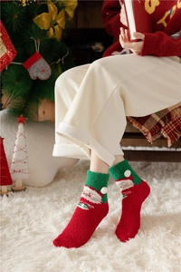 Detail of plush Christmas coral fleece socks with Santa Claus pattern and white pom poms