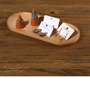 Macro view of oval wooden jewelry tray with two cone-shaped ring holders and earrings