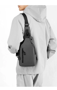 Male model wearing a dark grey waterproof chest bag with black strap and metal zippers