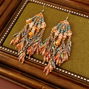 Detail of vintage bohemian tassel earrings with pink and teal crystal beads on velvet