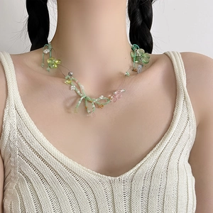 Close-up of green and pink beaded floral necklace with bow accents on a model