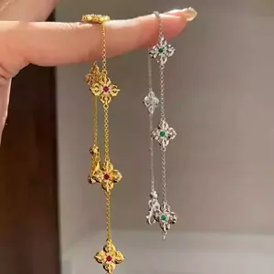 Detail of 14k gold plated clover bracelets with red and green gemstone inlays