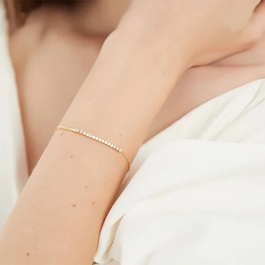 Close-up of minimalist gold plated S925 silver bracelet with sparkling zircon cubes on wrist