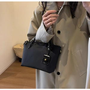 Detail view of large black oxford tote with crossbody strap and small charm purse