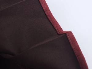 Détail macro du tissu en tweed rouge foncé avec coutures précises et finition mate