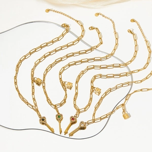 Detail view of five gold paperclip necklaces with heart-key pendants and colorful stones