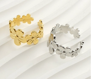 Detailed close-up of gold and silver open daisy rings on white textured background