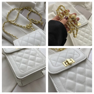 Close-up of white quilted leather bag with gold chain strap and metal lock detail