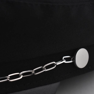 Détail macro de la chaîne en argent et visière en cuir sur casquette noire en coton