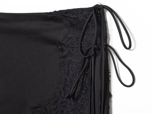 Close-up of black satin dress featuring eyelash lace trim and drawstring side detail