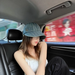 Detail view of denim newsboy cap with white stripes and side metal button decoration