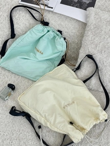 Lightweight mint green and yellow drawstring backpacks with embroidered logo in a flat lay