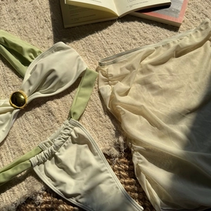 Detail of three-piece bikini set with gold buckle and sheer mesh beach cover-up