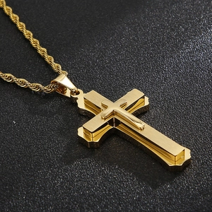 Detail of a golden double-layered cross pendant with a textured finish and rope chain