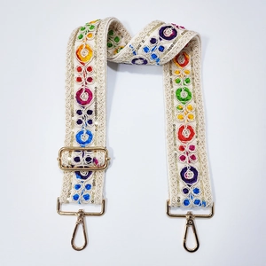 Close-up of bohemian guitar style strap with colorful embroidery and gold metal hooks