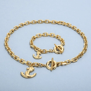 Detailed view of gold anchor pendant necklace and bracelet set with toggle clasp