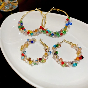 Detail of colorful crystal beads and pearls woven on golden hoop earrings set