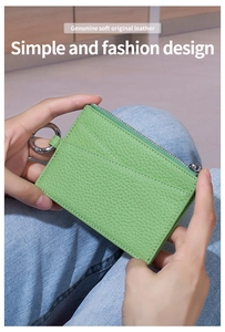 Detail of green litchi grain genuine leather coin purse with metal ring held by hands