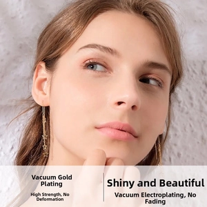Close-up of long star tassel earrings in 18K gold plating on model with soft lighting