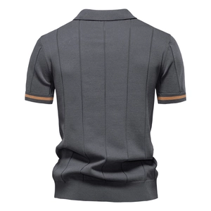 Dettaglio polo in maglia grigio scuro con texture a pieghe verticali e bordi marroni a righe