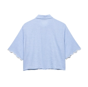 Detail of light blue textured fabric shirt featuring scalloped edge sleeve design