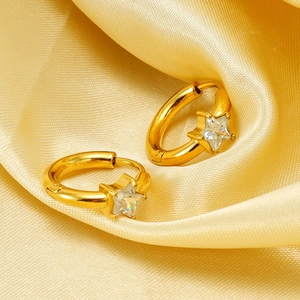 Vue macro de boucles d'oreilles créoles dorées avec étoile en zircon sur satin