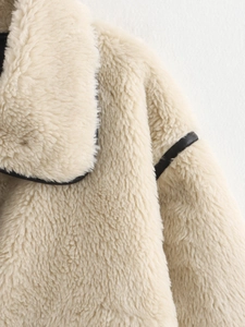 Detail of beige faux shearling jacket with black leather piping and lapel design