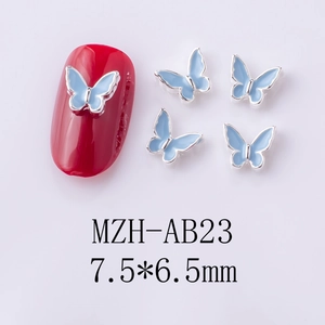 Macro detail of blue alloy butterfly nail art charms measuring 7.5x6.5mm on red nails