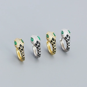 Detail of snake hoop earrings with sparkling zircons and green enamel eyes in gold and silver