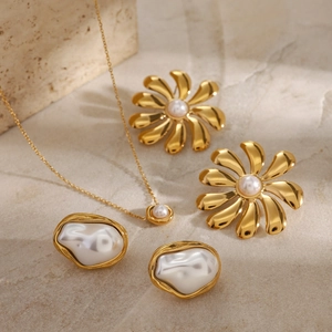 Detailed flat lay of gold pearl jewelry set with flower earrings and necklace on stone