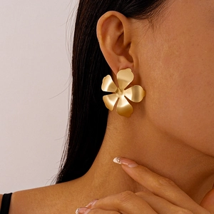 Macro side view of a large matte gold floral earring worn by a model in a fashion shot