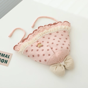 Detail der Baby-Strickmütze mit Spitzenkante, Kirsch-Anhängern und großer Schleife