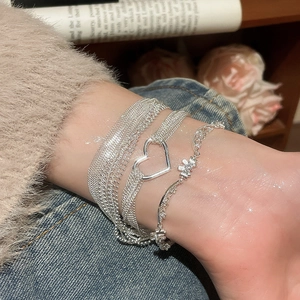 Detail of layered silver heart bracelet with lace pattern on model's wrist