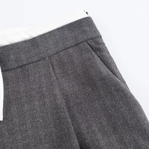 Macro detail of herringbone fabric texture and waistband stitching on grey trousers