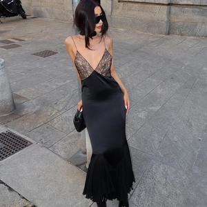 Outdoor street view of a black lace-up mermaid dress with silk-like finish and lace detail