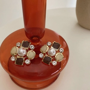 Macro shot of vintage pearl flower earrings with enamel petals and crystal accents
