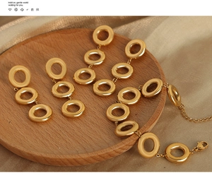 Detail of gold circular link earrings and bracelet set displayed on a wooden tray