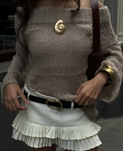 Foto de estilo callejero de un suéter de punto beige sin hombros y minifalda plisada