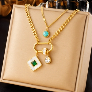 Close-up of double-layered gold stainless steel necklace with emerald and zircon pendants