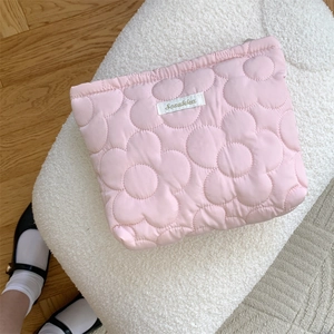 Detailed view of pink floral quilted makeup bag with Sozakka label on soft white stool